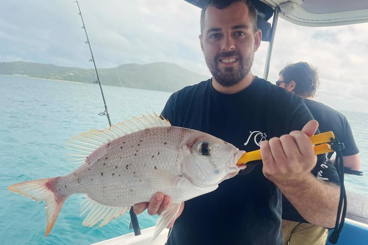 a man holding a fish in the water